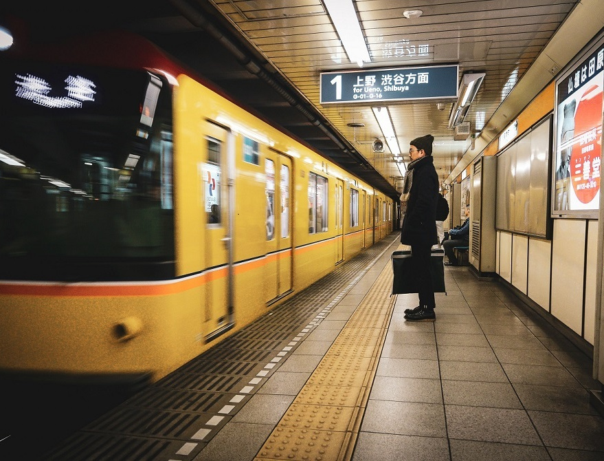 駅のホームで電車を待つ男性